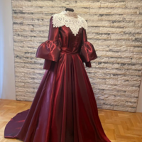 Elegancka suknia wieczorowa w kolorze bordowym umieszczona manekinie - bogato zdobiona koronkami