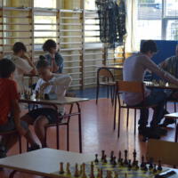 Na sali gimnastycznej prrzy stolikach zawodnicy grają w szachy