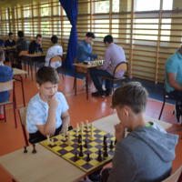 Na sali gimnastycznej prrzy stolikach zawodnicy grają w szachy