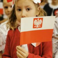 Obchody Narodowego Święta Niepodległości w Szkole Podstawowej w Marcinkowicach - dziewczynka z biało-czerwoną chorągiewką.