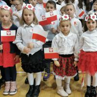 Obchody Narodowego Święta Niepodległości w Szkole Podstawowej w Marcinkowicach - dzieci na sali gimnastycznej wymachują biało-czerwonymi chorągiewkami