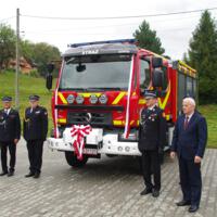Uroczystość poświęcenia nowego samochodu strażackiego w OSP Paszyn.
Strażacy oraz przewodniczący Rady Gminy Chełmiec po obu stronach nowego wozu strażackiego.