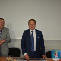 Wójt gminy oraz Minister Andrzej Gut-Mostowy stoją na sali za stołem.