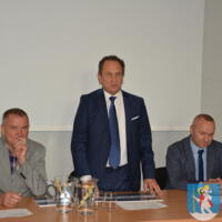Wójt gminy oraz pan Marcin Bulanda siedzą za stołem a Minister Andrzej Gut-Mostowy stoi.
