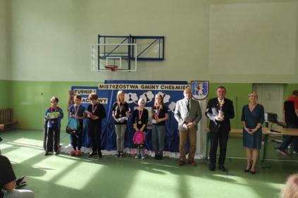 Wspólne zdjęcie zawodników z Wójtem i przewodniczącym Komisji Kultury Andrzejem Tyrklem oraz dyrektorką szkoły, zawodnicy są udekorowani medalami oraz trzymają w rękach nagrody, w tle tablica z napisem Mistrzostwa Gminy Chełmiec