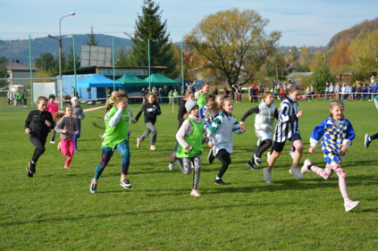 Dzieci biegną po trawiastym boisku - w tle widoczna wiata klubu LKS Marcinkowice