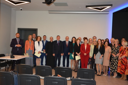 Wspólne zdjęcie ustawionych w rządku nagrodzonych nauczycieli oraz wójta gminy i przewodniczącego rady gminy oraz dyrektora GZE w Chełmcu